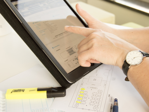 Sachbearbeiter In einem mobilen Computer liest ein Mitarbeiter Daten eines Schiffs. Vor ihm liegt ein Platzierungsplan des Schiffs.