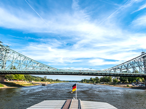 Ein Dampfer fährt stromab und hat gerade das Blaue Wunder passiert. Es ist windig, zeigen die Wellen auf der Elbe, aber es scheint auch die Sonne.