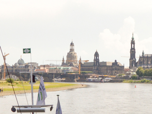 A steamboat sails upstream through the Marienbrücke (Marien Bridge). A complete panorama of the city is visible—including the Semper Opera House, the tower of the Kreuzkirche (Church of the Holy Cross), the Hausmann Tower (Hausmannsturm), the Town Hall Tower, the Cathedral Tower, the tower of the Estates House (Ständehaus), the Frauenkirche (Church of Our Lady), and the dome of the Academy of Fine Arts.