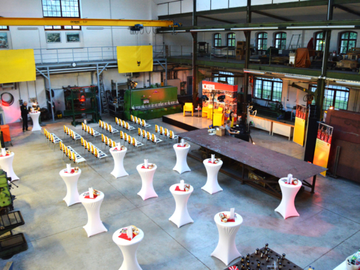 Blick in die Maschinenhalle der Werft in Dresden-Laubegast. Eine Bühne ist aufgebaut, zehn Stehtische mit weißen Hussen sind aufgebaut, dahinter stehen Stühle wie im Theater.