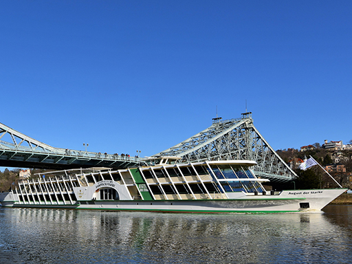 MS August the Strong The saloon ship August der Starke is currently passing through the Blue Wonder in Dresden-Blasewitz. Here, the ship is still wearing the colors white and green. The upper half of the image is filled with a bright blue sky.