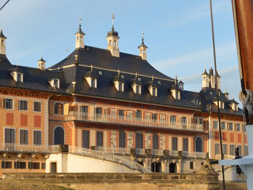Ein Dampfer fährt an Schloss Pillnitz vorbei. Die Sonne strahlt, der Himmel ist blau.
