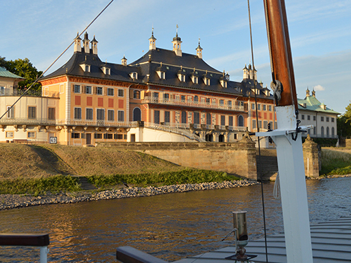 Ein Dampfer fährt an Schloss Pillnitz vorbei. Die Sonne strahlt, der Himmel ist blau.