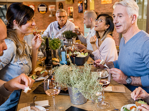 Mehrere Menschen stoßen mit Weingläsern an,