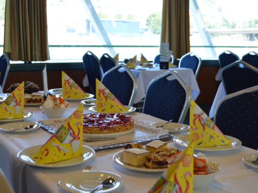 An invitingly set table with a cake and pie. A table set with a cake, a fruit bowl and a cake plate.