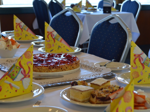 Ein gedeckter Tisch mit einer Torte, einer Obstschale und einem Kuchenteller.