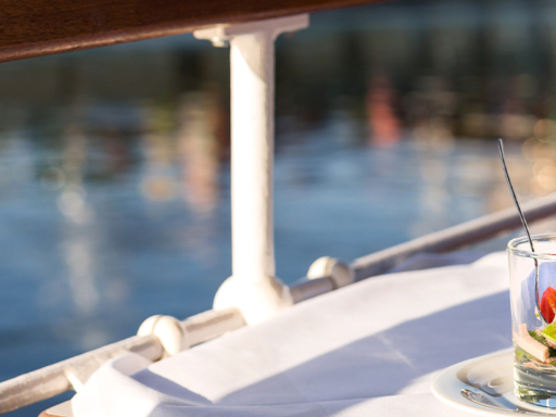 Auf einem Tisch eines Dampfers stehen eine Vorspeise im Glas und ein Glas Wein.