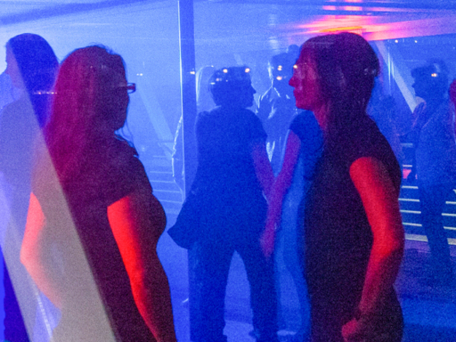 Party in einem Motorschiffs. Menschen tanzen, blaues Licht beleuchtet die Szenerie.