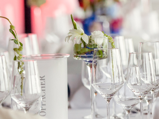 Schön gedeckter Tisch mit Blumengestecken in pink und blau, weißen Servietten und vielen Gläsern.