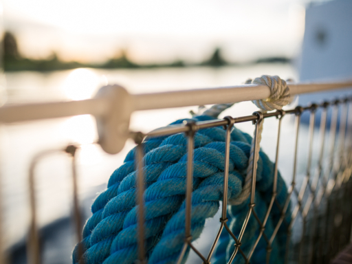 Ein aufgewickeltes dickes blaues Seil hängt an einer weißen Schiffsreling.
