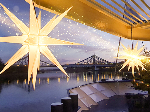 Auf einem Salonschiff, das elbaufwärts fährt und gleich das Blaue Wunder erreicht, hängen zwei weiße Herrnhuter Sterne.