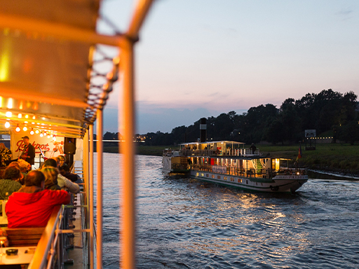 Zwei Dampfer begegnen sich auf der Elbe. Es ist Abend. Beide Schiffe sind beleuchtet. Auf einem davon spielt eine Band auf dem Oberdeck, Passagiere sitzen da und hören zu.