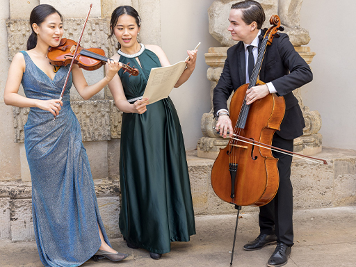 Ein Trio des DRESDNER RESIDENZ ORCHESTERs präsentiert leichte Klassik. Eine Frau spiel Violine, ein junger Mann Cello und eine weitere Frau hält die Noten.