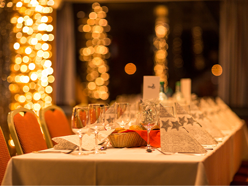 Auf einem festlich gedeckten Tisch stehen Brotkörbe und viele Gläser bereit. Besteck liegt da und weihnachtliche Servietten sind aufgestellt.