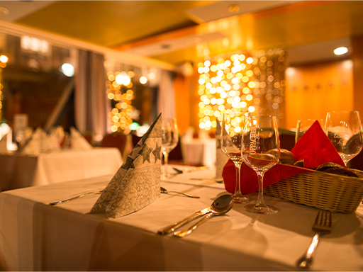 Ein festlich gedeckter Tisch mit einem Brotkorb, Besteck, Servietten und mehreren Gläsern.