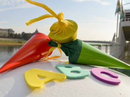 Drei bunte Zuckertüten und große Buchstaben liegen auf einer weißen Fläche und laden zu einer Zuckertütenfahrt per Schiff ein.