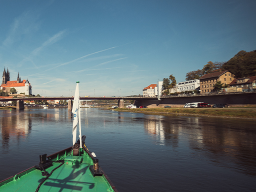 Ein Dampfer fährt stromab und erreicht in wenigen Minuten Meißen. Voraus ist die alte Autobrücke in Meißen, links ist die Albrechtsburg zu sehen. Der Himmel ist blau, es ist windstill.