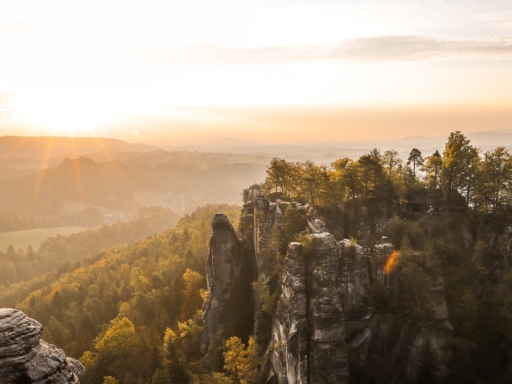 Sandsteinfelsen der Sächsischen Schweiz im Sonnenschein. Die Formation befindet sich nahe dem Kurort Rathen. Das Licht ist rötlich und warm, im Vordergrund sind mehrere Felsnadeln zu sehen.