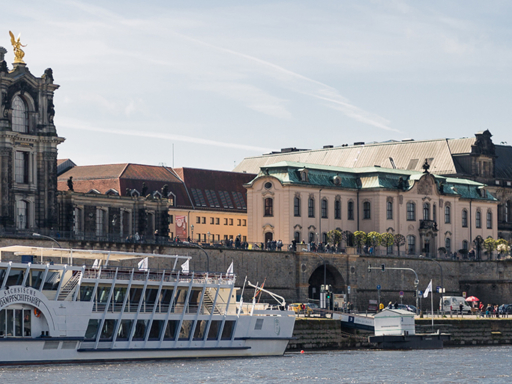 View of the historic old town. A steamer and a saloon boat are moored on the terraced bank. It's sunny, but there are also a few clouds.