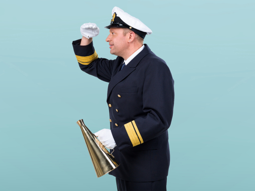 Ein Mann in nautischer Uniform und mit einem Sprechtrichter in der Hand schaut in die Ferne.