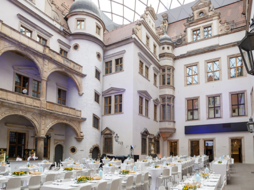 Blick in den geschmückten Hof des Dresdner Schlosses. Dort stehen gedeckte weiße Tische und Stühle, der Hof ist für ein Bankett vorbereitet.