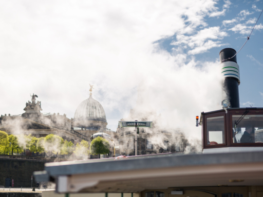 A steamer moored in front of the Terraced Bank. White smoke rises and drifts toward the shore. Visible in the smoke are the Brühl Terrace and the dome of the Art Academy.