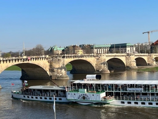 The steamer Dresden is sailing downstream on the Elbe in radiant sunshine and is about to pass the Augustus Bridge. In the background, the Church of the Three Kings can be seen.