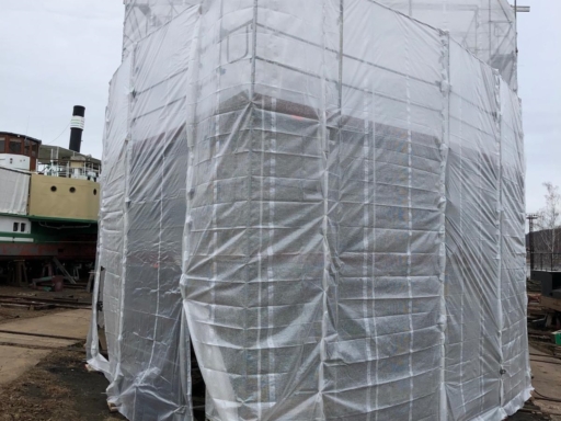 Front Aufnahme vom Bug eines Salonschiffs auf der Werft. Das Schiff ist eingerüstet und das Gerüst mit Folien bespannt.