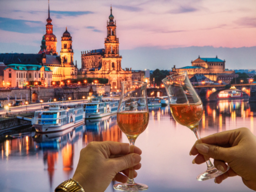 Zwei Personen stoßen mit Whisky vor der Skyline Dresdens an. Aufgenommen wurde dieses Bild auf einem Dampfer. Im Hintergrund sieht man anliegende Schiffe am Terrassenufer.