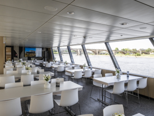 Das Conference Deck im hinteren Teil eines Salonschiffs mit großen Bildschirmen ermöglicht konzentrierte Tagungen. Die Tische sind weiß, die Stühle ebenso.