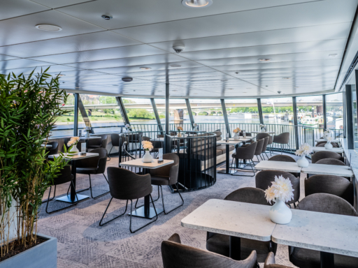 Der Fine Dining Club im Oberdeck eines Salonschiffs. Das ist der Raum für besonders festliche Anlässe mit Blick in Fahrtrichtung des Schiffs. Helle Farben bestimmen das Ambiente.