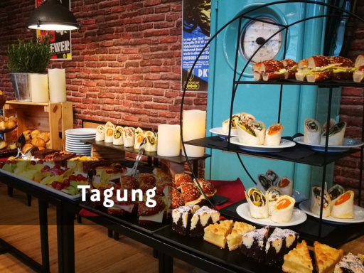 Ein Buffett mit halbierten Wraps, belegten Brötchen, Kuchen und einer Obstplatte.