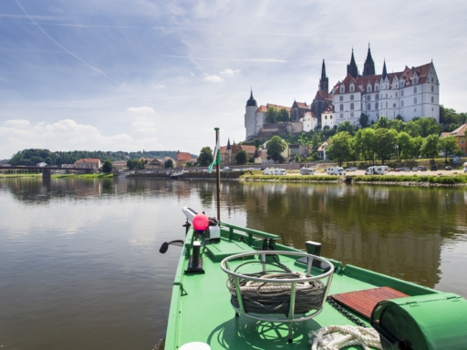 Blick vom Dampfe auf den grünen Bug des Schiffs. Es fährt flussaufwärts vorbei an der Albrechtsburg in Meißen.
