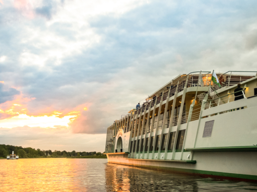Ein Salonschiff fährt in den Sonnenuntergang, in der Ferne nähert sich ein Dampfer.