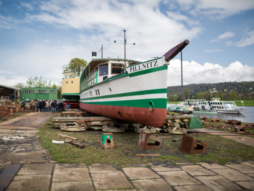 Der Dampfer Pillnitz liegt auf der Werft in Laubegast. Recht unten fährt ein Salonschiff die Elbe entlang.