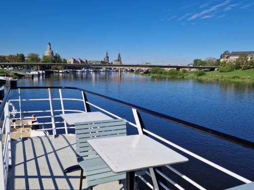 20240423_093451 Ein Salonschiff auf der Elbe. Das Foto auf dem Sonnendeck zeigt die neuen mintfarbenen Sitzgelegenheiten und weiße Tische. Es ist sonnig, die Elbwiesen sind grün.
