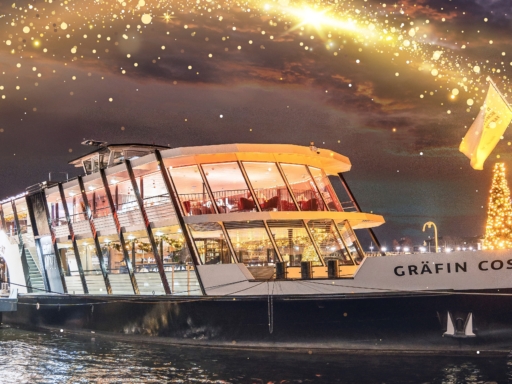 Das Salonschiff Gräfin Cosel bei Nacht am Terrassenufer, Das Schiff ist erleuchtet und weihnachtlich geschmückt. Auf dem Bug steht ein beleuchteter Weihnachtsbaum.